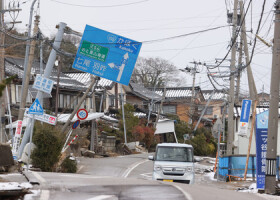 液状化とみられる影響で、波打つ道路と傾いた家や電柱＝１月１６日、石川県内灘町