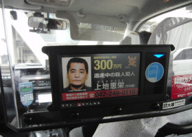 タクシーの車内モニターに流れる、元暴力団組員上地恵栄容疑者の手配写真＝２０１２年１０月、東京都内