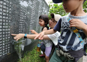 「平和の礎」を訪れ、高祖父の名前を指す子どもら＝２３日、沖縄県糸満市の平和祈念公園