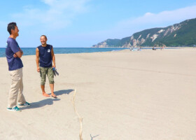 広がった砂浜で話す大石賢斉さん（右）＝６月２１日、石川県輪島市町野町