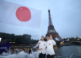 開会式でセーヌ川を進む船上で、エッフェル塔を背に日の丸を振る日本選手団旗手の江村美咲と半井重幸（右）＝２６日、パリ（ＡＦＰ時事）
