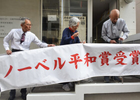 日本原水爆被害者団体協議会のノーベル平和賞受賞決定を祝う横断幕を掲示する箕牧智之代表委員（右端）ら＝５日午後、広島市中区