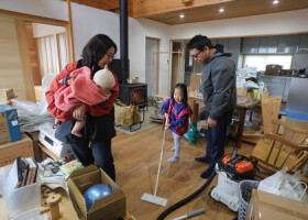 津波を受けた室内の掃除や片付けをする藤部巴さん（左奥）と夫の裕太さん（右）。中央は長女ふみちゃん。左手前は抱えられる長男麦ちゃん＝２０２４年１２月８日、石川県珠洲市