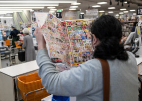 東京都内のスーパーで、チラシをチェックする買い物客＝２０２４年４月（ＡＦＰ時事）