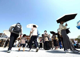 大阪・関西万博のパビリオン前で日傘を差して並ぶ人たち＝１９日午後、大阪市此花区
