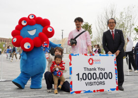 大阪・関西万博で１００万人目の来場者として家族とともに記念品を受け取る宮森信さん（右から２人目）＝２３日午後、大阪市此花区