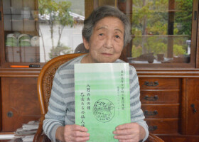 自身の戦争体験が記された冊子を持つ佐野睦子さん＝５月２２日、岩手県釜石市