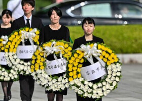 ６日、広島市で行われた平和記念式典で、慰霊碑にささげる花輪を手にする参列者たち（ＡＦＰ時事）