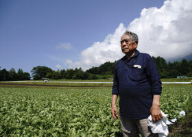 自身が開拓した土地に立つ市川渥夫さん。現在、市川さんから畑を借り受けた農家がレタスを栽培する＝７月２３日、長野県軽井沢町