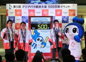 カウントダウンボードの前に立つ（左から）広沢一郎名古屋市長、大村秀章愛知県知事、パラ自転車男子の川本翔大。右端はアジアパラ大会マスコットの「ウズミン」＝５日、名古屋市中区