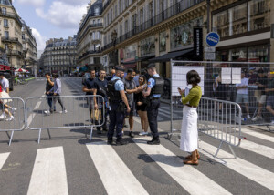 ２４日、五輪開会式を控えたパリで、ルーブル美術館に向かう人々を確認する警察官（ＥＰＡ時事）